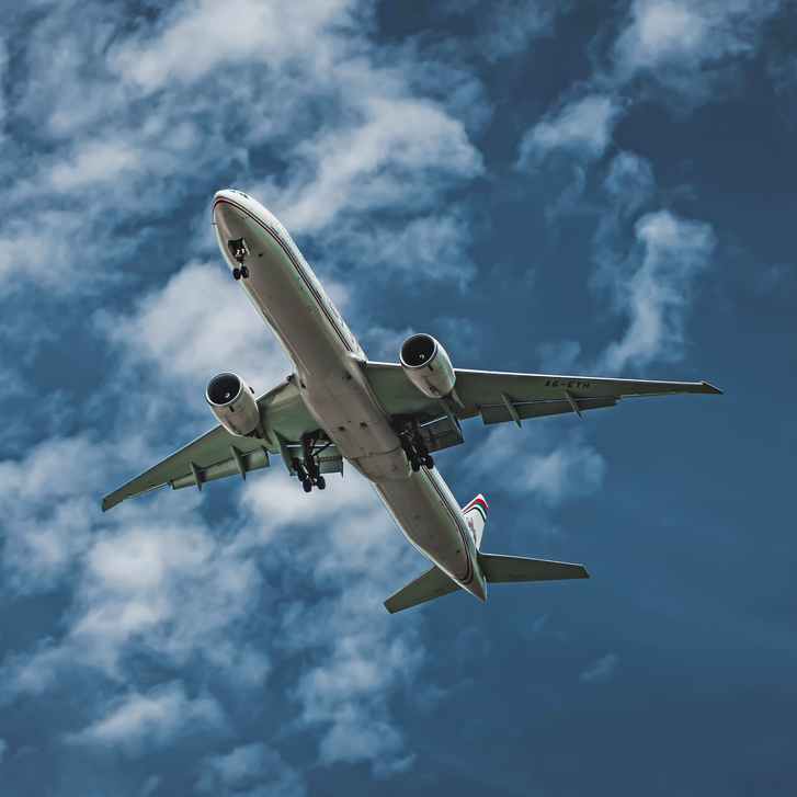 White and Blue Airplane Under Blue Sky and White Clouds